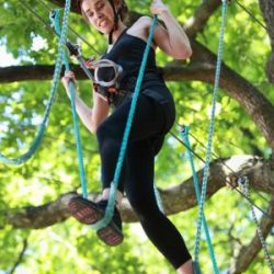 Eine Frau mit ängstlichem Gesicht im Baum eines Kletterparks.