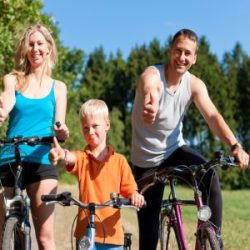 Eine junge Familie auf ihren Fahrrädern und hält den Daumen in die Höhe.