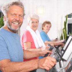 Senioren trainieren fröhlich auf dem Crosstrainer.