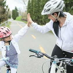 Mutter und Tochter fahren gemeinsam Rad und klatschen sich ab.