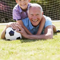 Opa und Enkel spielen fröhlich mit dem Fußball.