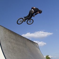 Ein Junge wagt mit dem Fahrrad einen Sprung auf einer Rampe.