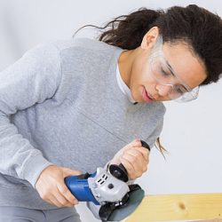 Junge Frau mit einer Schleifmaschine