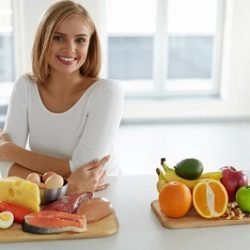 Frau mit verschiedenen Lebensmitteln an einem Tisch