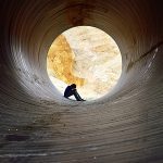 Mann sitzt depressiv im Tunnel.